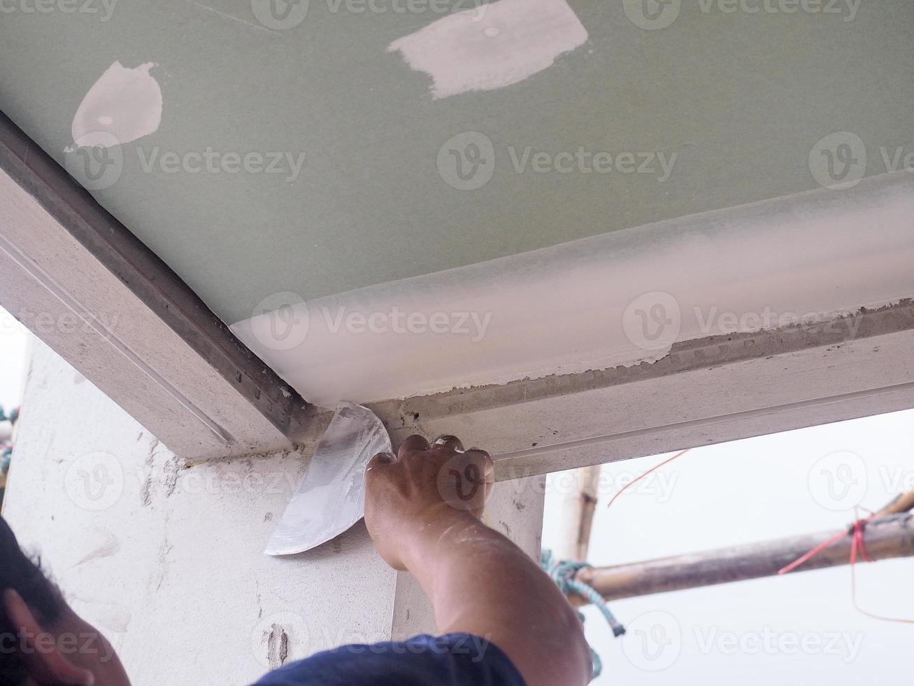 The ceiling worker is plastering the ceiling joints with high quality white gypsum plaster to keep the joints together. photo