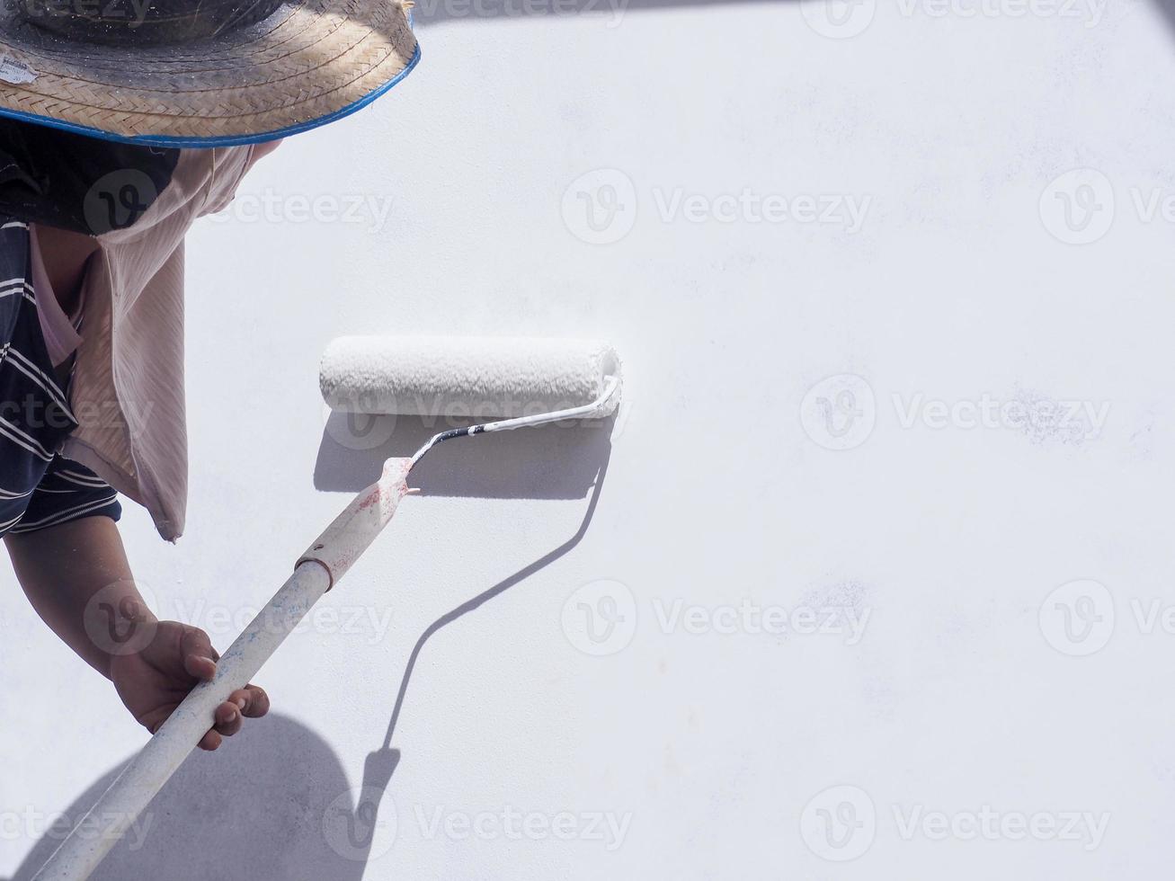 A worker is painting the walls of the house with a primer using a paint roller. photo