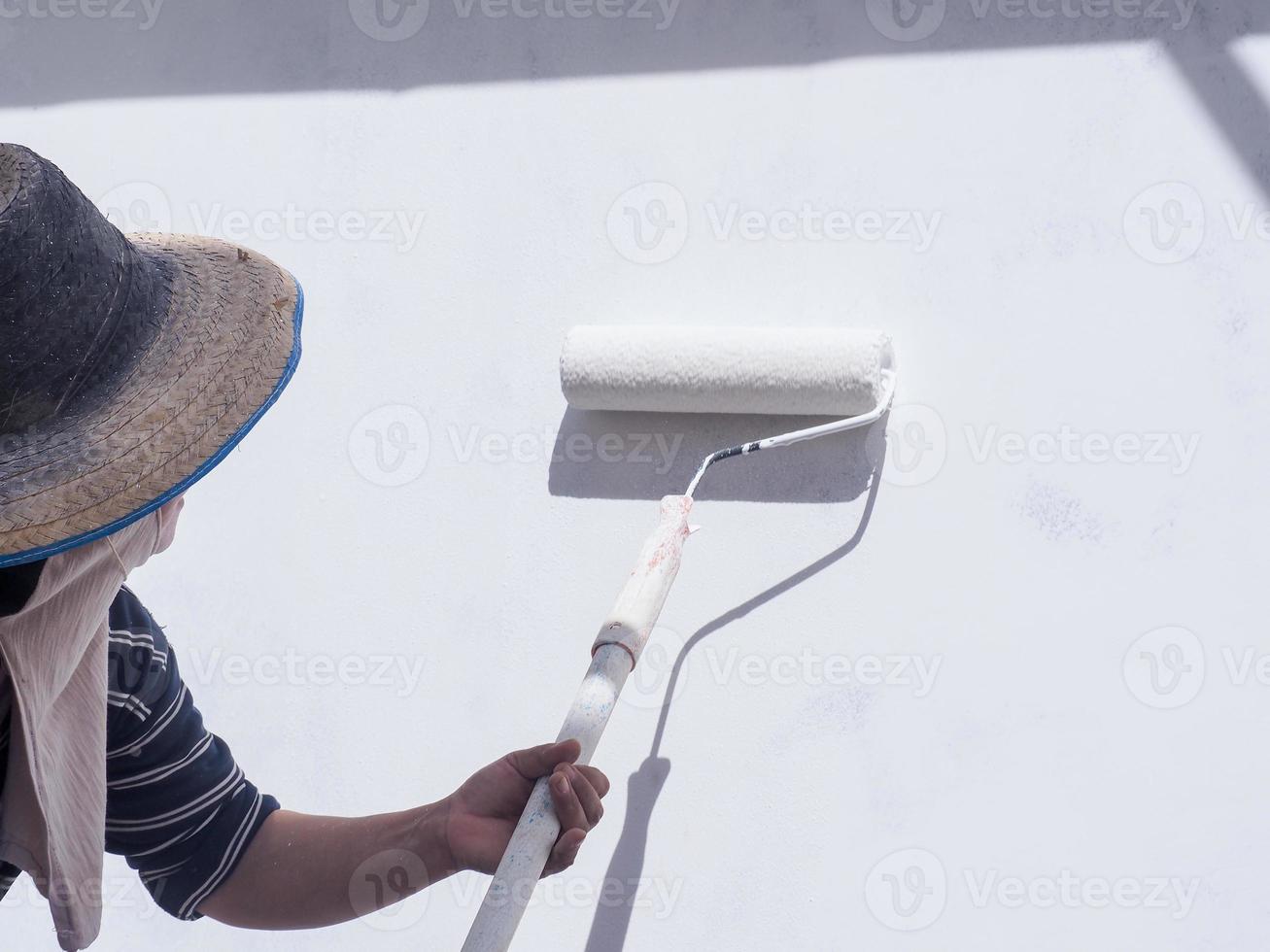 A worker is painting the walls of the house with a primer using a paint roller. photo