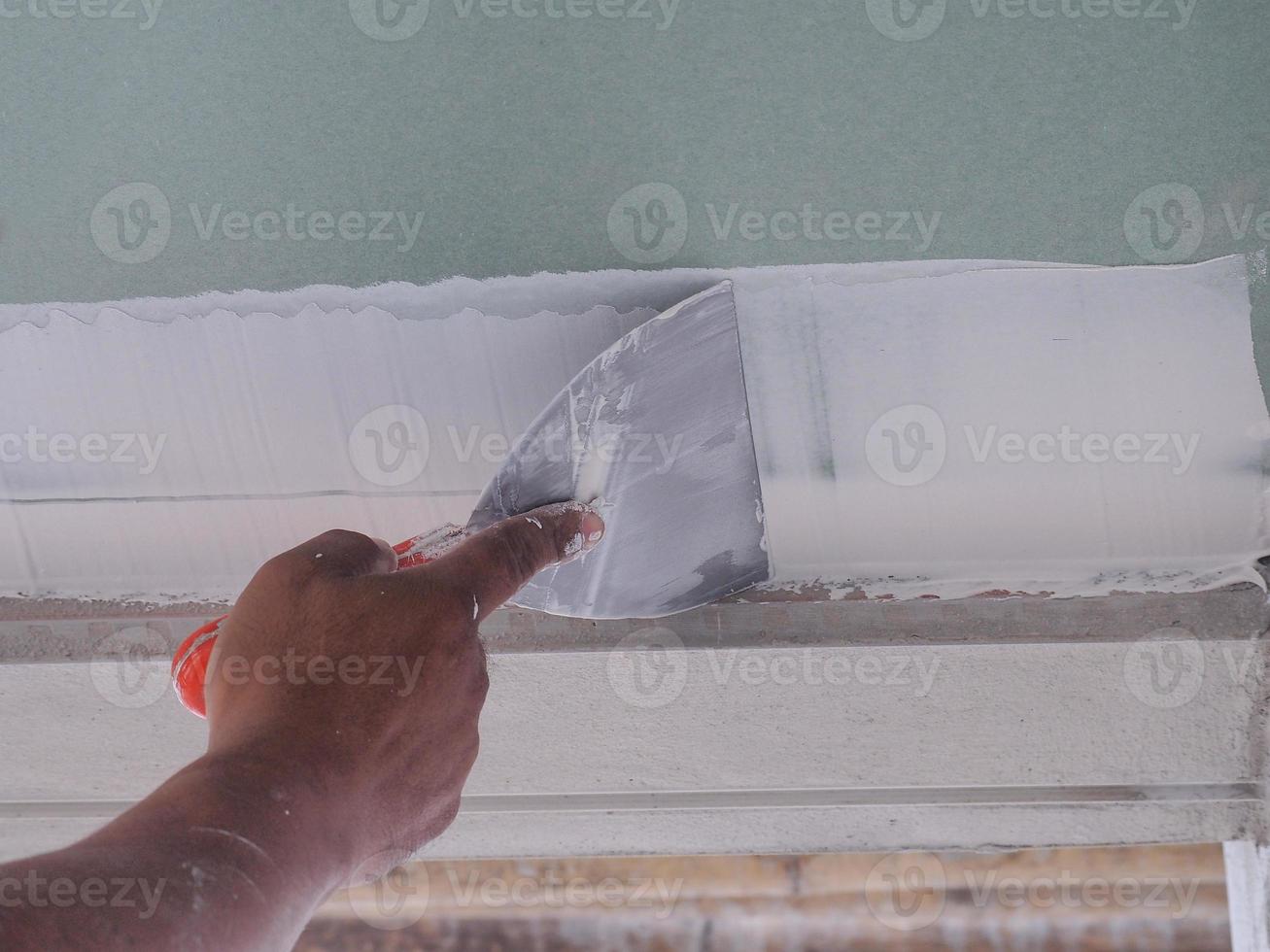 The ceiling worker is plastering the ceiling joints with high quality white gypsum plaster to keep the joints together. photo