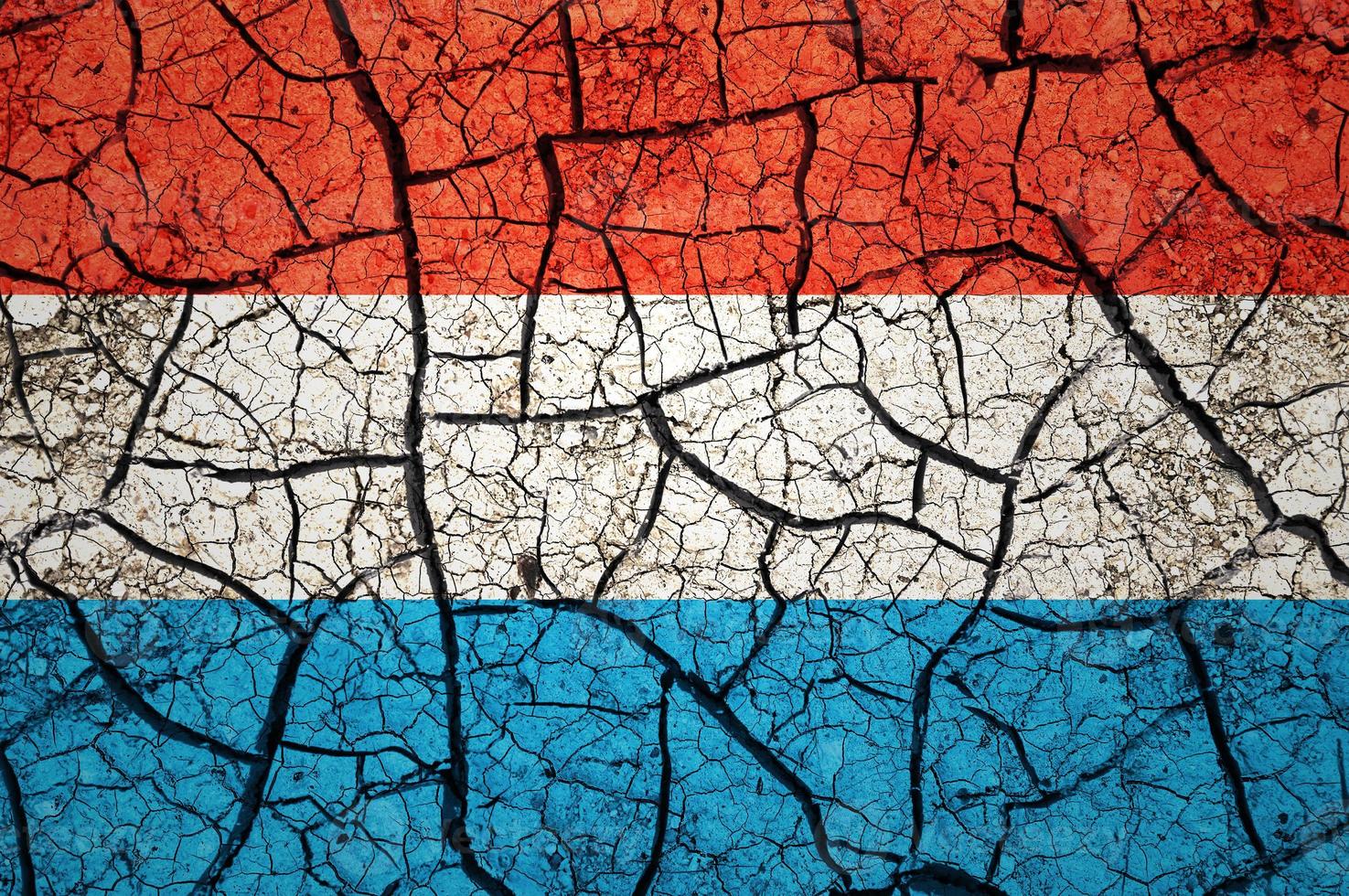 Dry soil pattern on the flag of Luxembourg. Country with drought concept. Water problem. Dry cracked earth country. photo