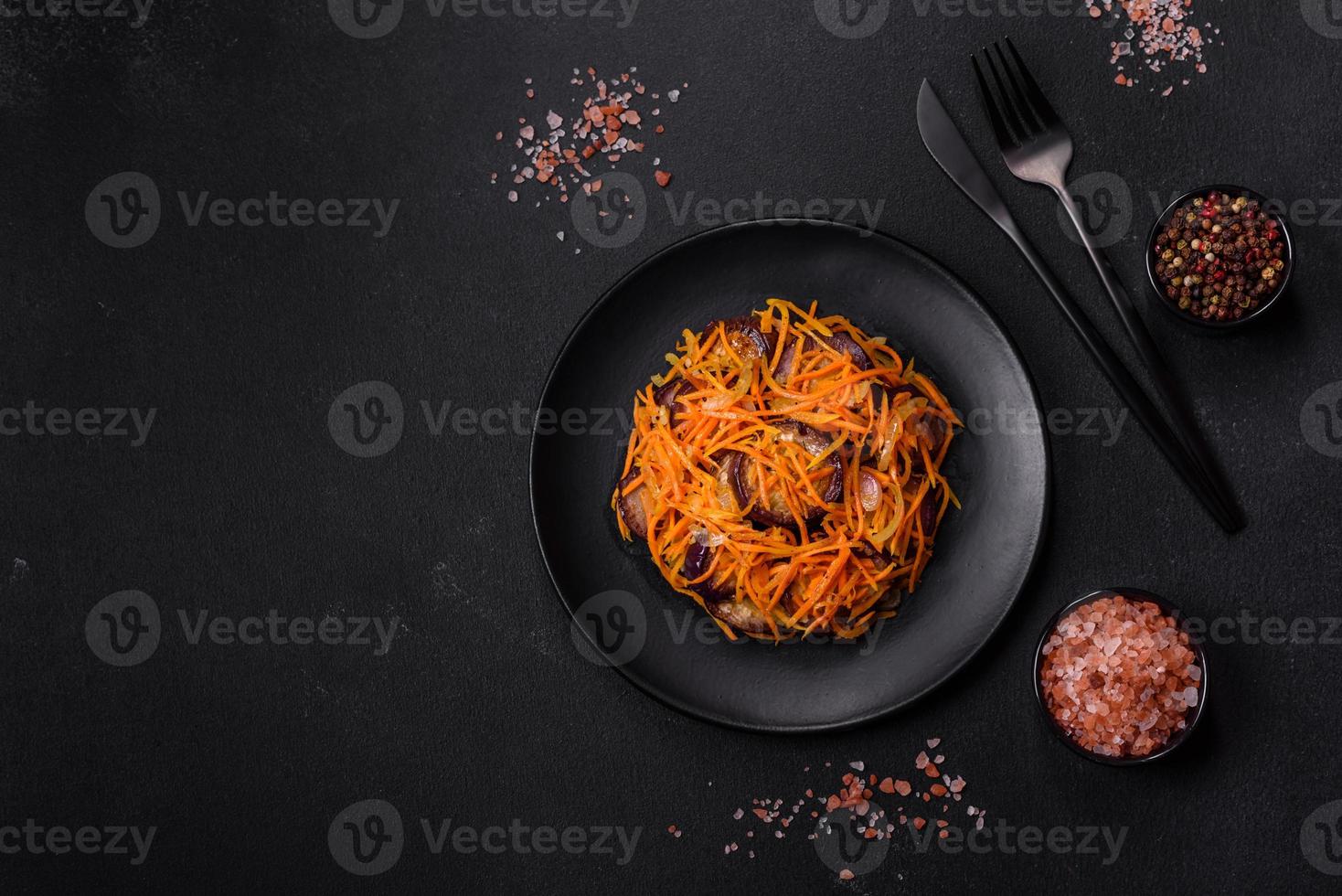 Korean salad with eggplant, carrots, garlic, spices and herbs on a dark concrete background photo