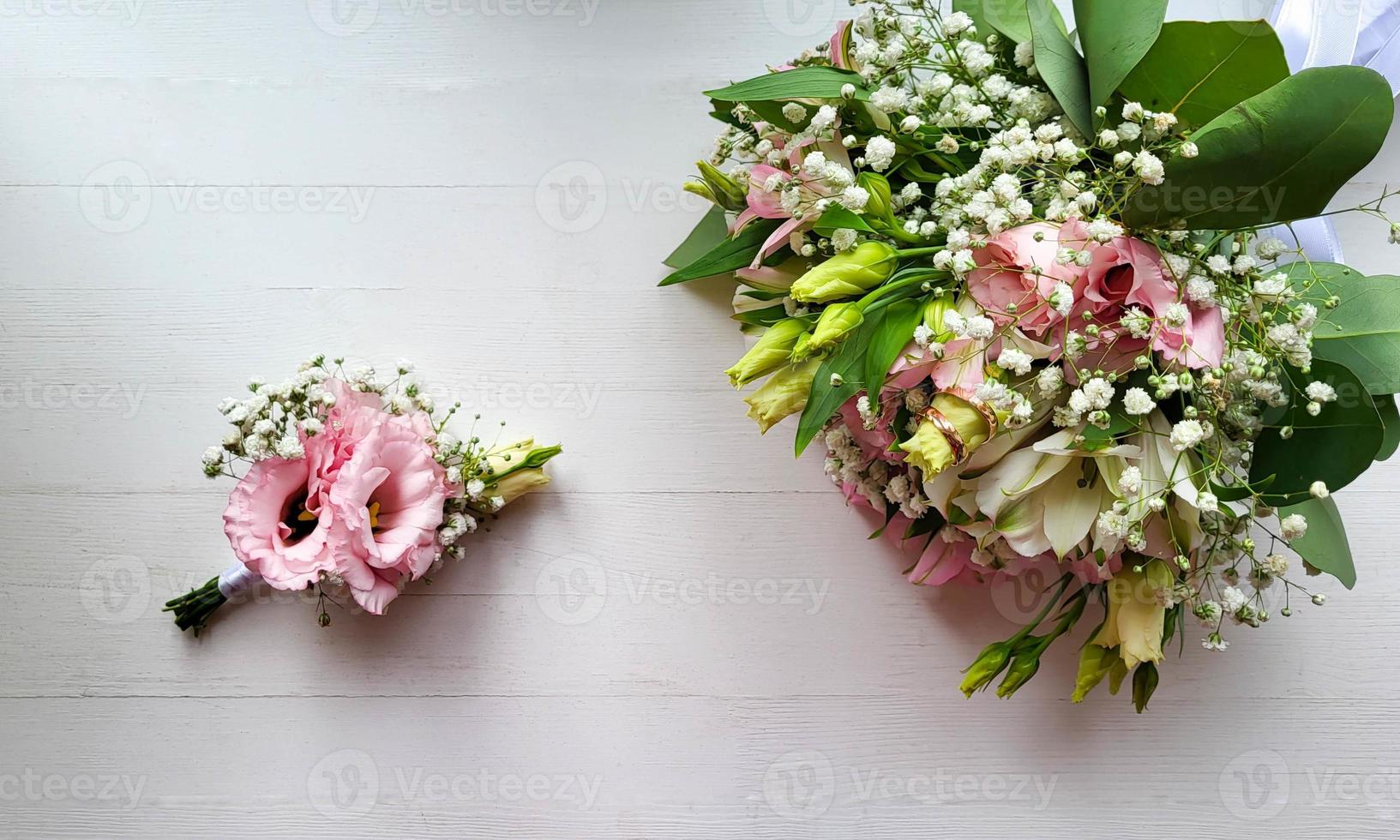 Two lovely wedding bouquets with gold rings on a white background photo