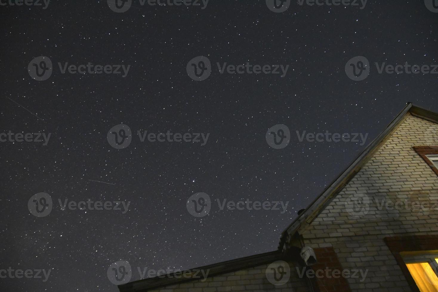 el cielo estrellado y los techos de las casas. astrofotografía en un pueblo con casas. foto