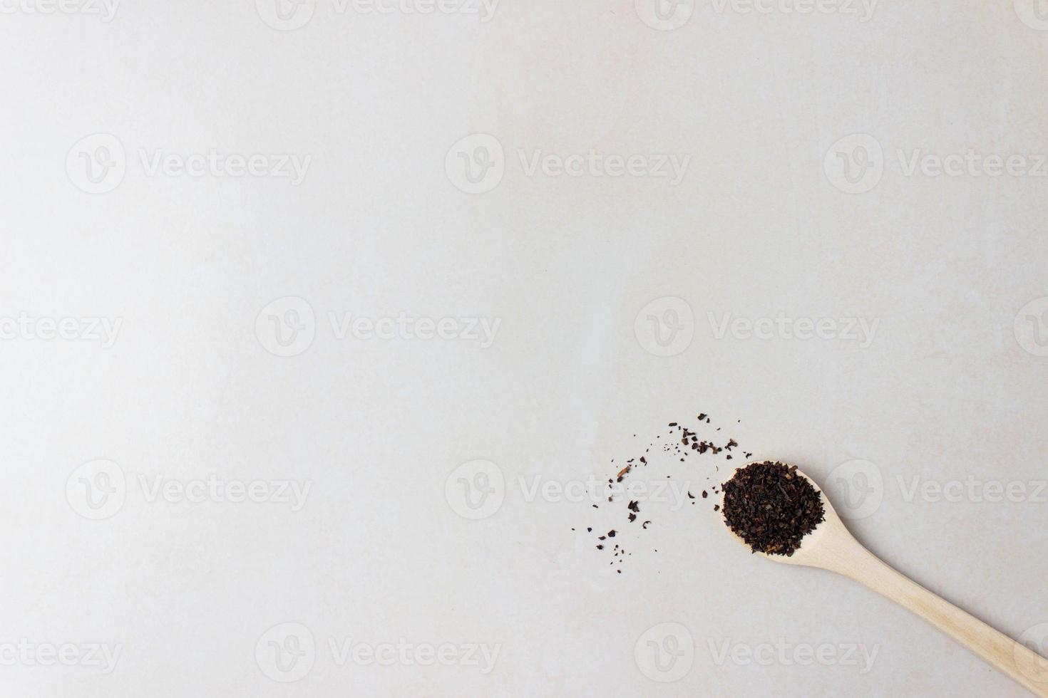 Wooden spoon on the table in the right is filled with dry tea leaves. Top view with copy space photo