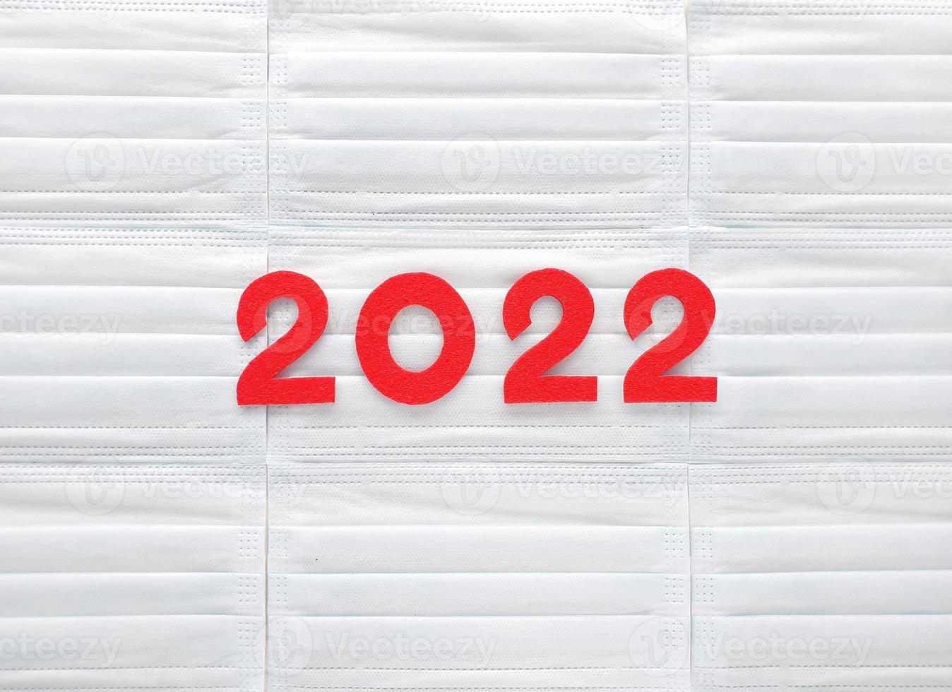 Red felt new year numbers 2022 on white medical masks background. Place for your text here. Review of the year results. photo