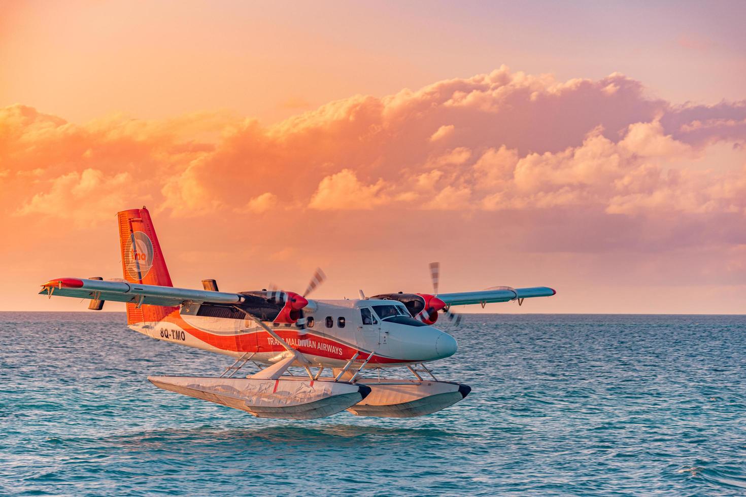 02.02.22, Ari atoll, Maldives Exotic scene with seaplane on Maldives sea landing. Seaplane over sunset sea before landing. Amazing sunset sky clouds, luxury travel, vacation transportation concept photo