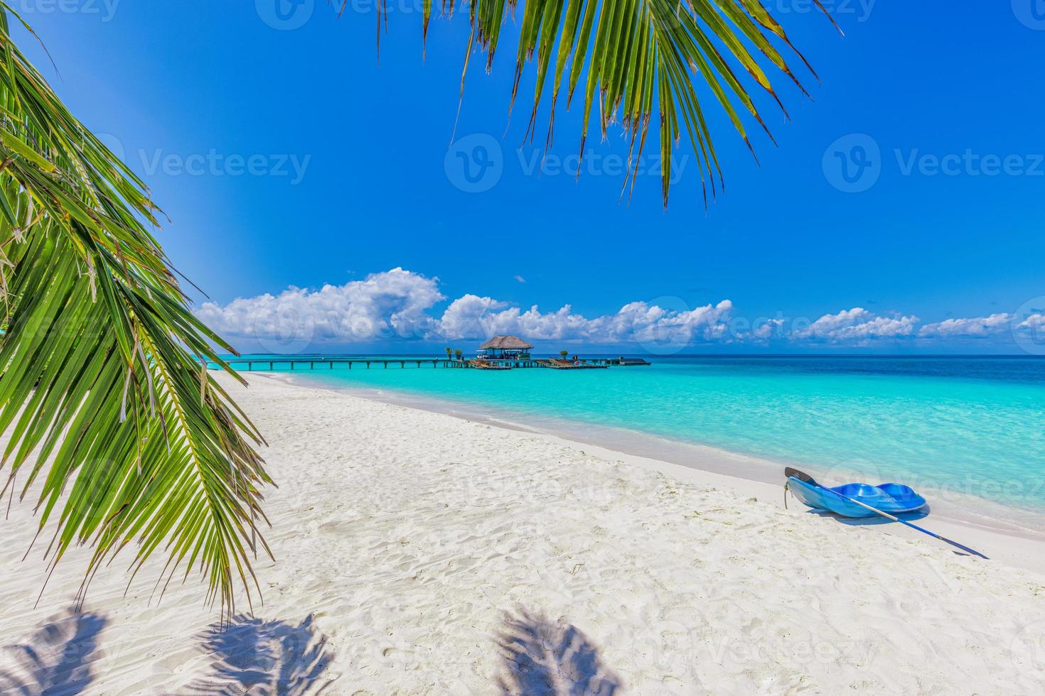 Maldives island beach with blue kayak on shore. Tropical landscape of summer, white sand with palm trees. Luxury travel vacation destination. Exotic beach landscape. Amazing nature, relax, freedom photo