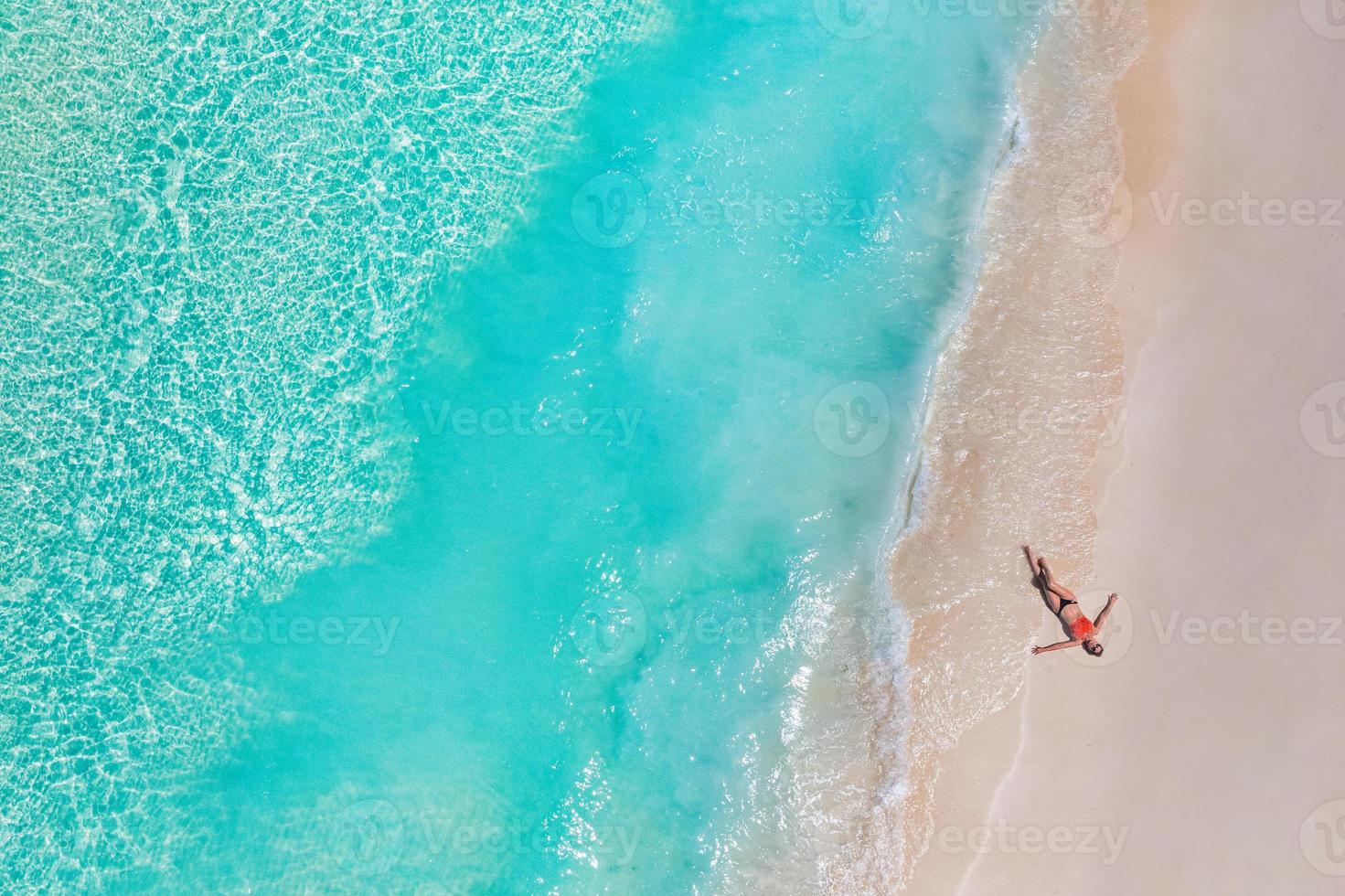 Aerial view of woman on the beach on Maldives islands. Vacation and adventure. Travel beach turquoise ocean water. Top view from drone, tropical azure sea and relax woman, carefree, freedom, relax photo