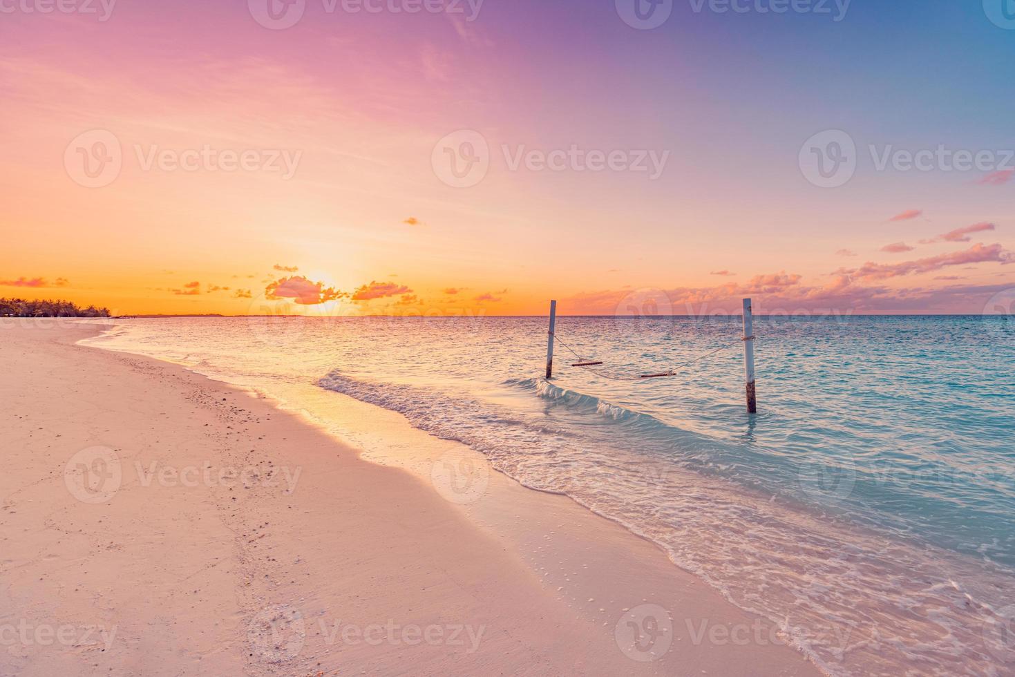Tropical sunset beach and sky background as exotic summer landscape with beach swing or hammock and white sand and calm sea beach banner. Paradise island beach vacation or summer holiday destination photo