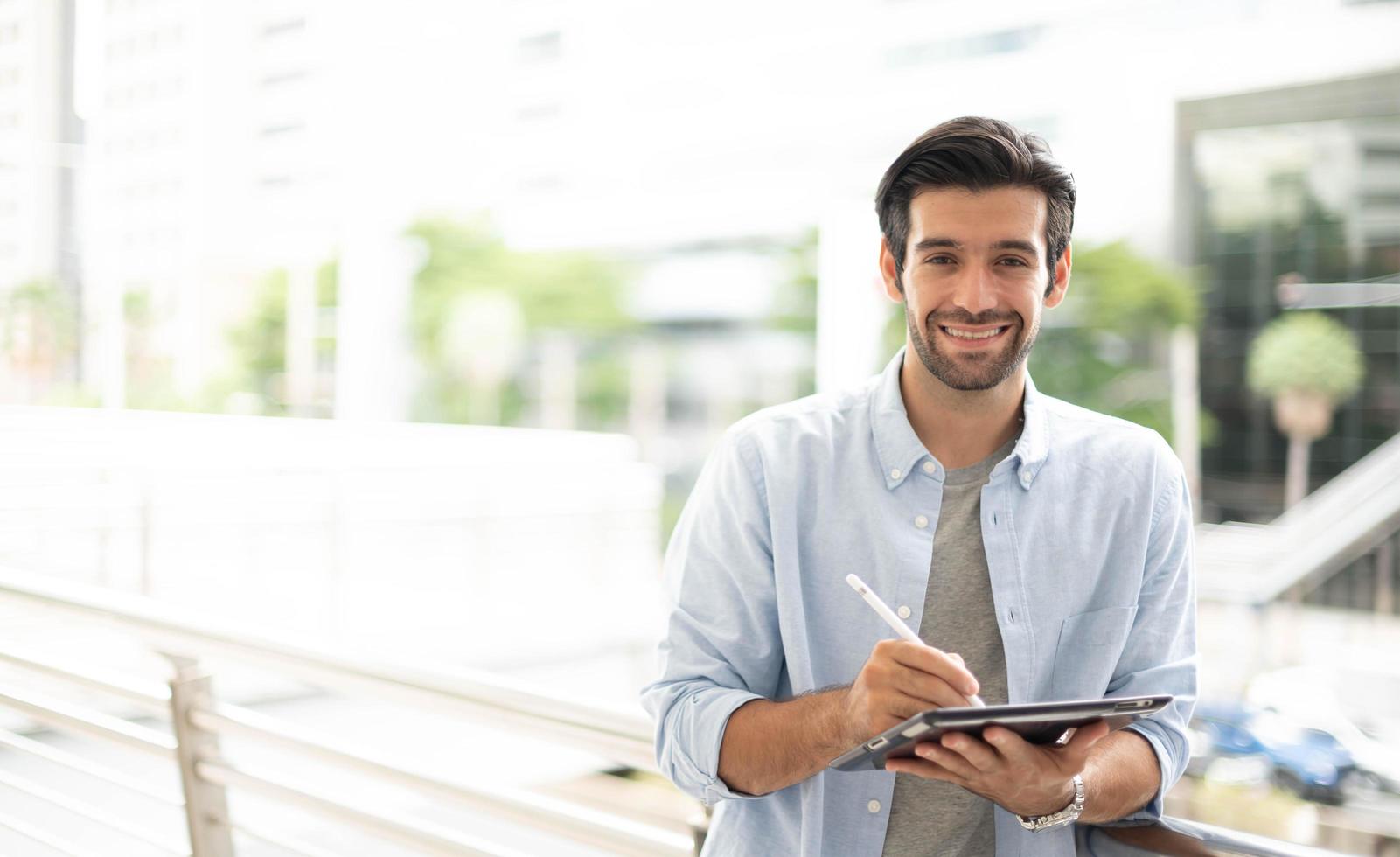 The young man using a tablet to working at out of office. The man wearing casual cloth and feeling relaxing and happy. photo