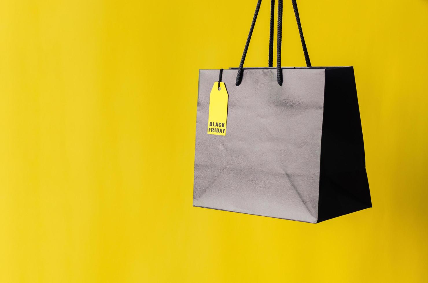 Black shopping bag with yellow price tag with yellow background for Black Friday shopping sale concept. photo
