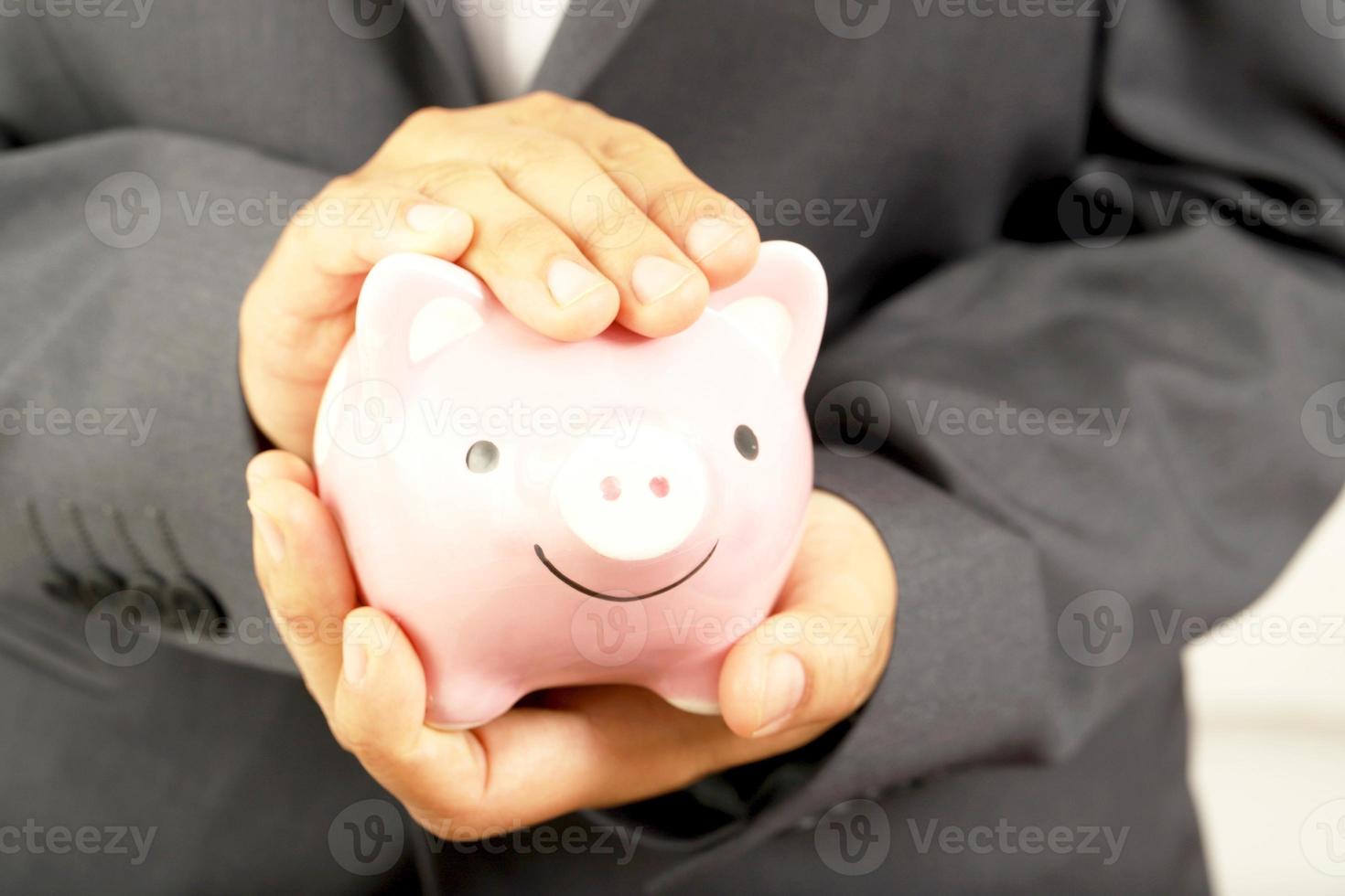 A businessman who has savings with a piggy bank photo