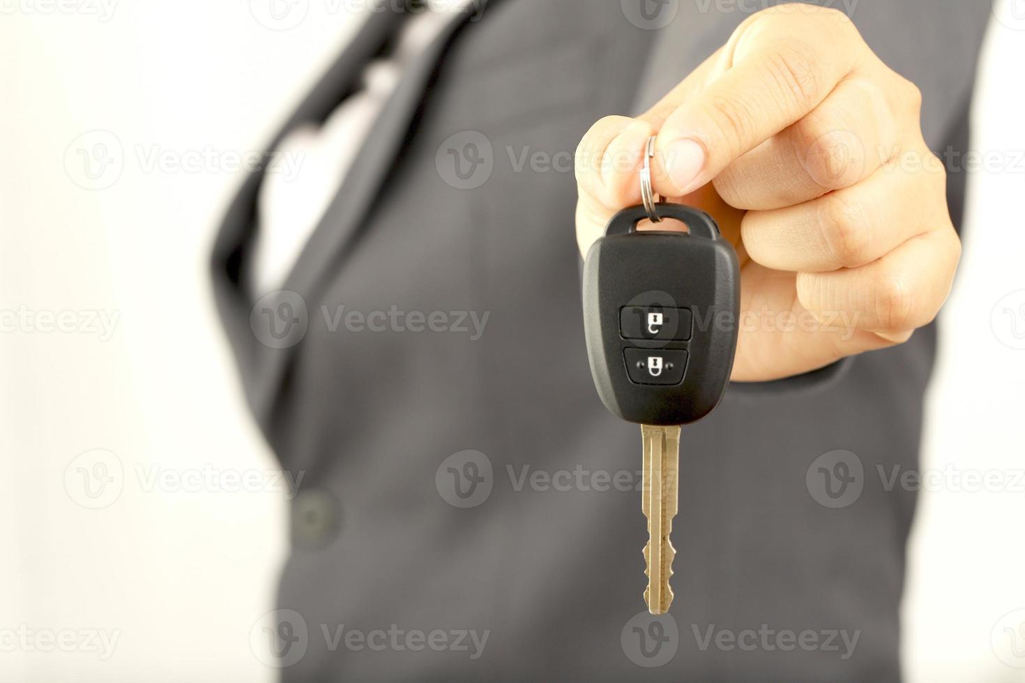 Salesman is carrying the car keys delivered to the customer at the showroom with a low interest offer. Special promotion photo