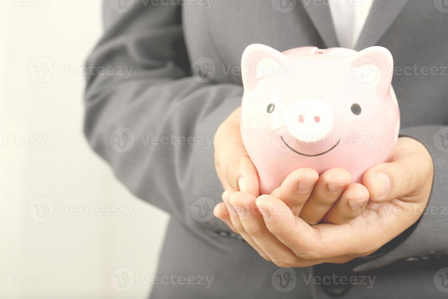 A businessman who has savings with a piggy bank photo