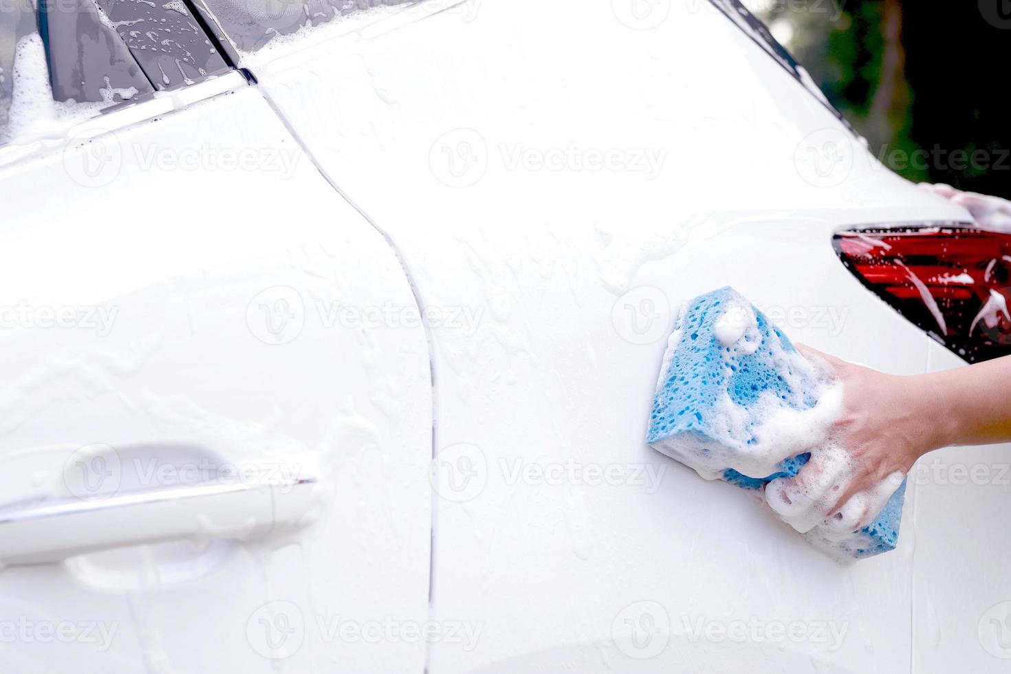 este hombre está lavando el auto y limpiando el auto. foto