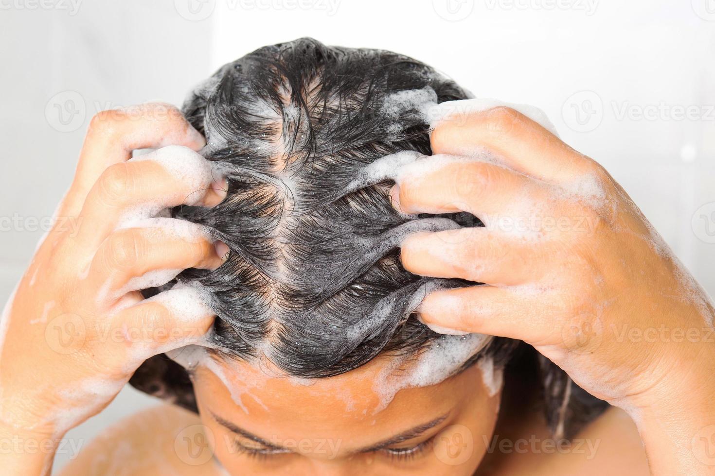 Asian woman washing her hair while taking a shower. photo