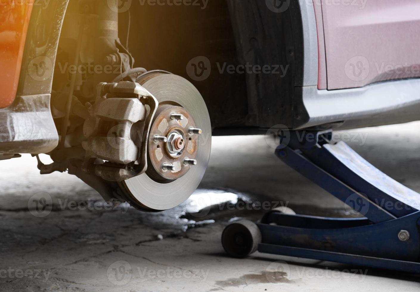 Replacing car wheel using hydraulic jack. car maintenance concept. Remove the wheels of the car in preparation for tire patch. brake discs without wheels. Automobile repair service center photo