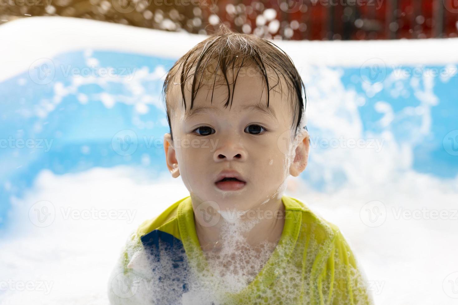 Cute little Asian boy swimming in bubbles in an inflatable pool. summer water play, family happiness, children's happiness, Pool and multi-colored balls photo