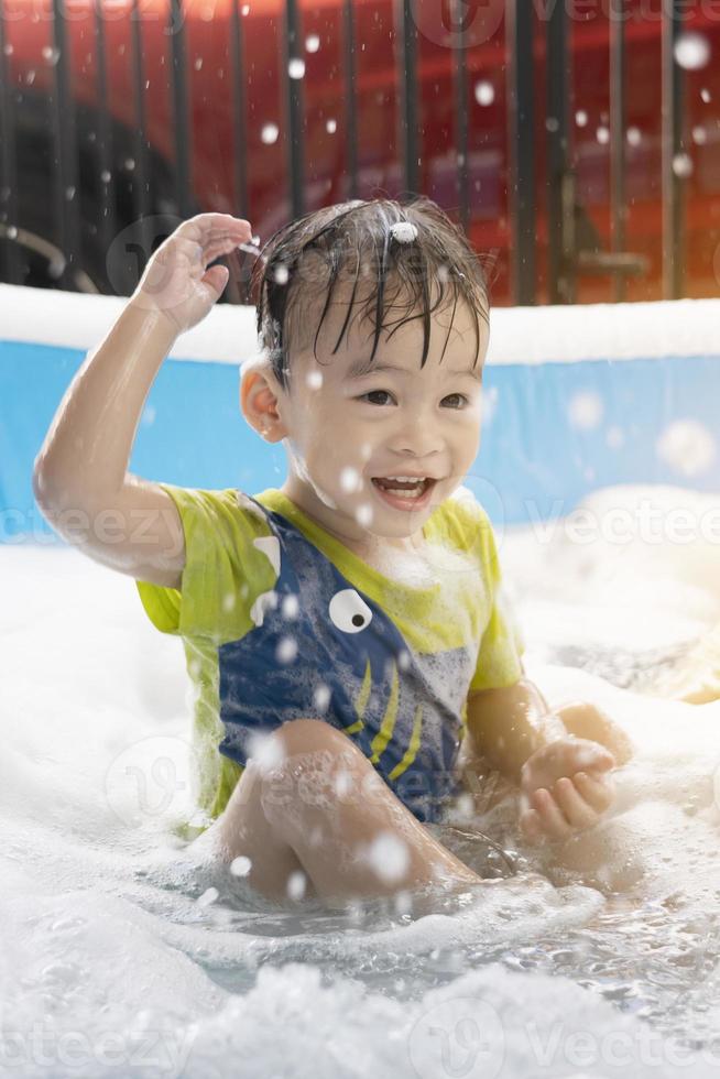 Children are happy to playing the water on the summer weekend. asian boy,  family, vertical, Children playing with soap bubbles in the swimming pool photo