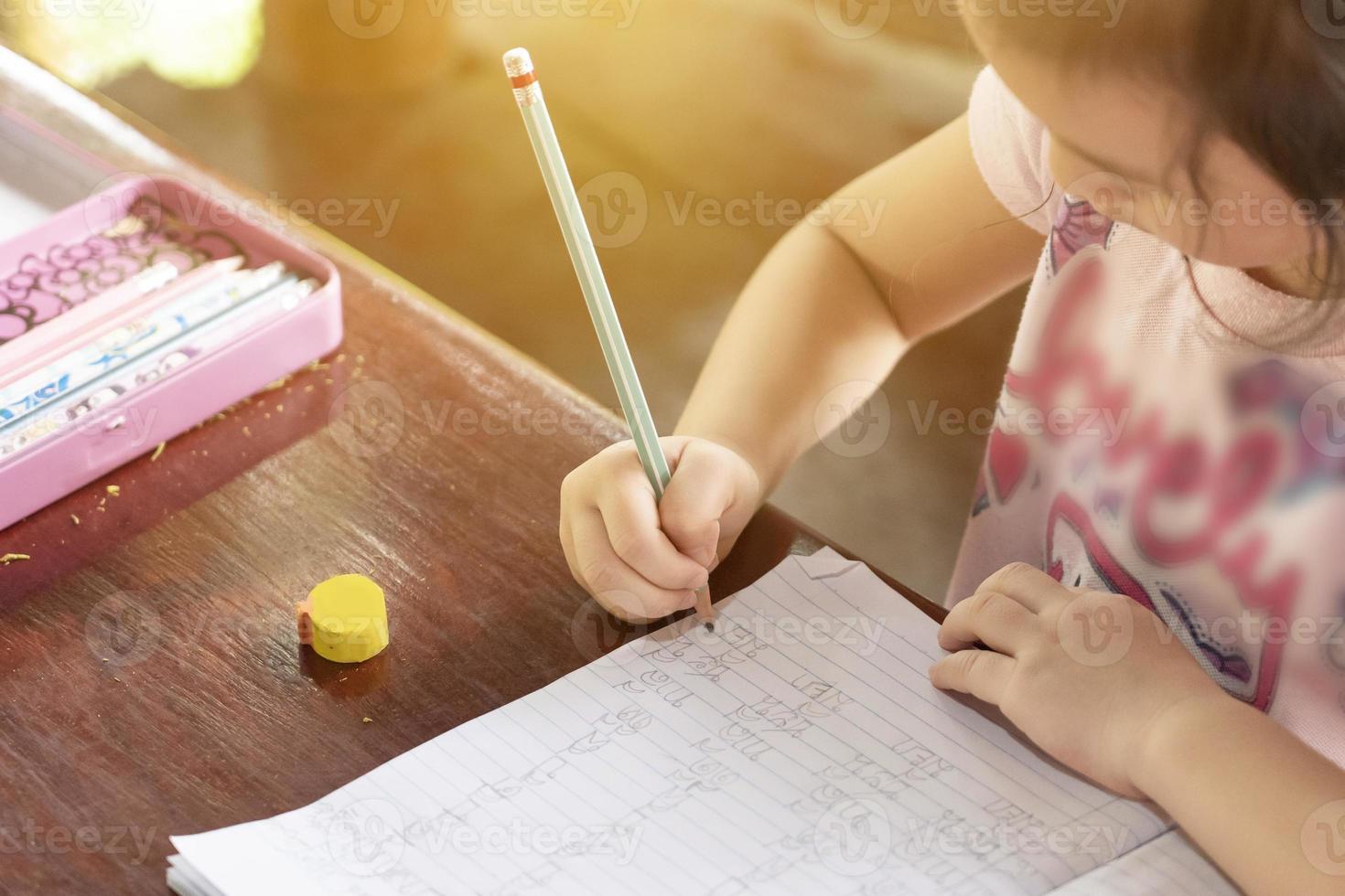 Asian girl sitting on a desk at home writing a book. online education