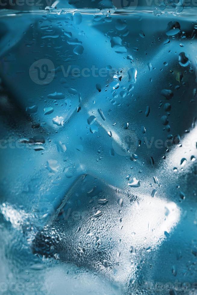 Ice cubes in a glass with crystal clear water on a blue background. Soft Selective Focus photo