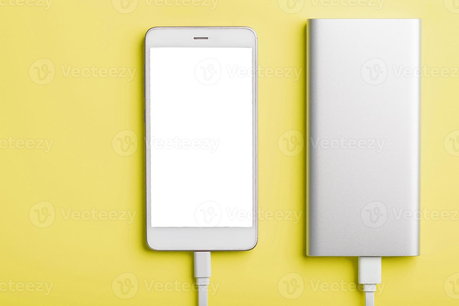 Power Bank charges your smartphone on a yellow background. Universal external battery for gadgets free space and minimalistic composition. photo