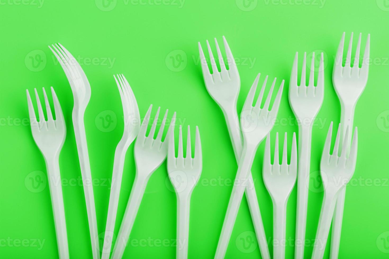 Disposable plastic tableware on a green background with free space. photo