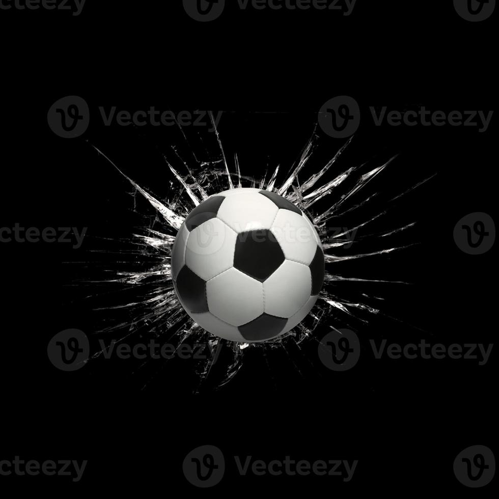 Fast soccer ball through broken glass on black background photo