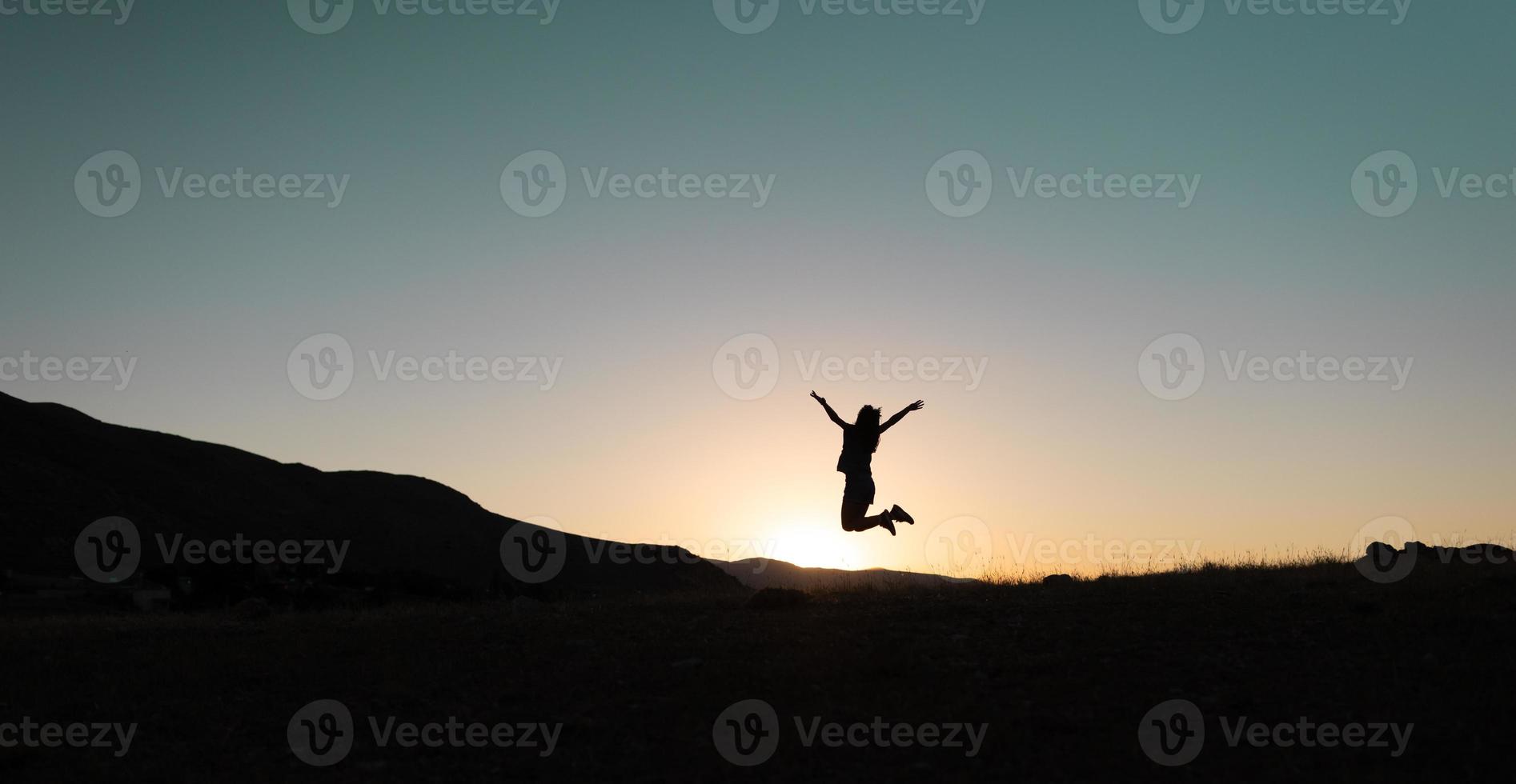 girl jumping at sunset in the mountains photo