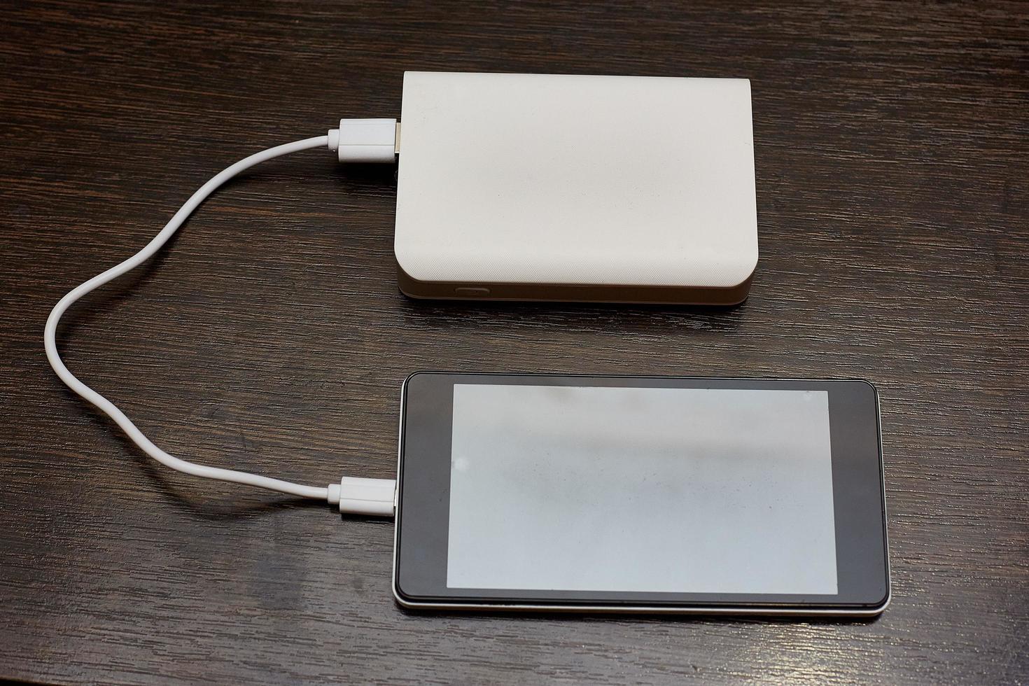 Smartphone charging with power bank on wood board photo