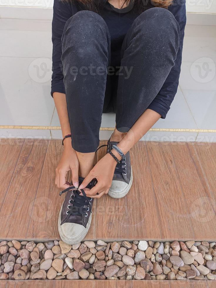 foot portrait of a young woman wearing and tying shoelaces on the porch of the house photo