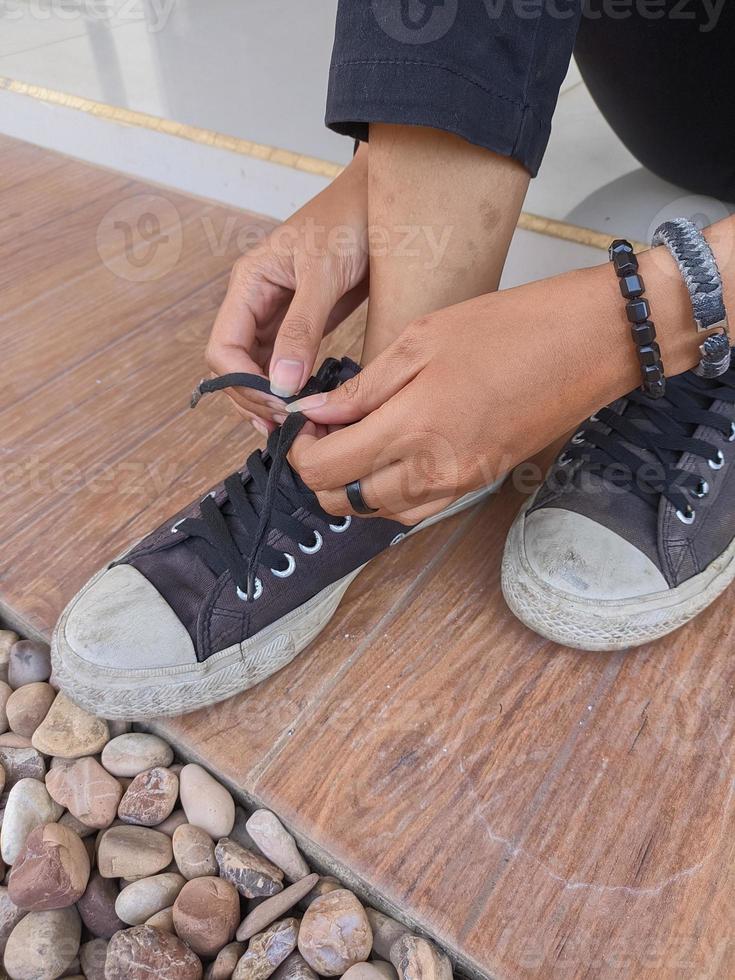 photo of female hands wearing and tying casual shoelaces