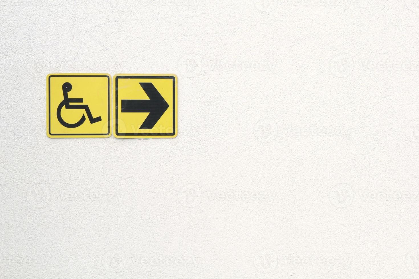 Yellow disabled sign and arrow right pointing sign on white background. Handicapped accessible sign of wheelchair. Concept of comfortable pathway for people barrier-free urban environment in city. photo