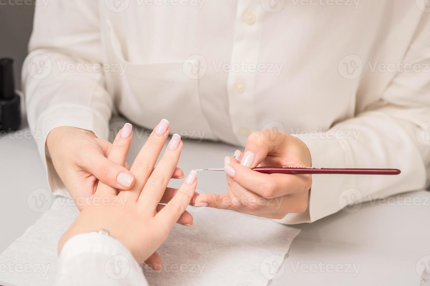 Woman receiving french manicure by beautician photo