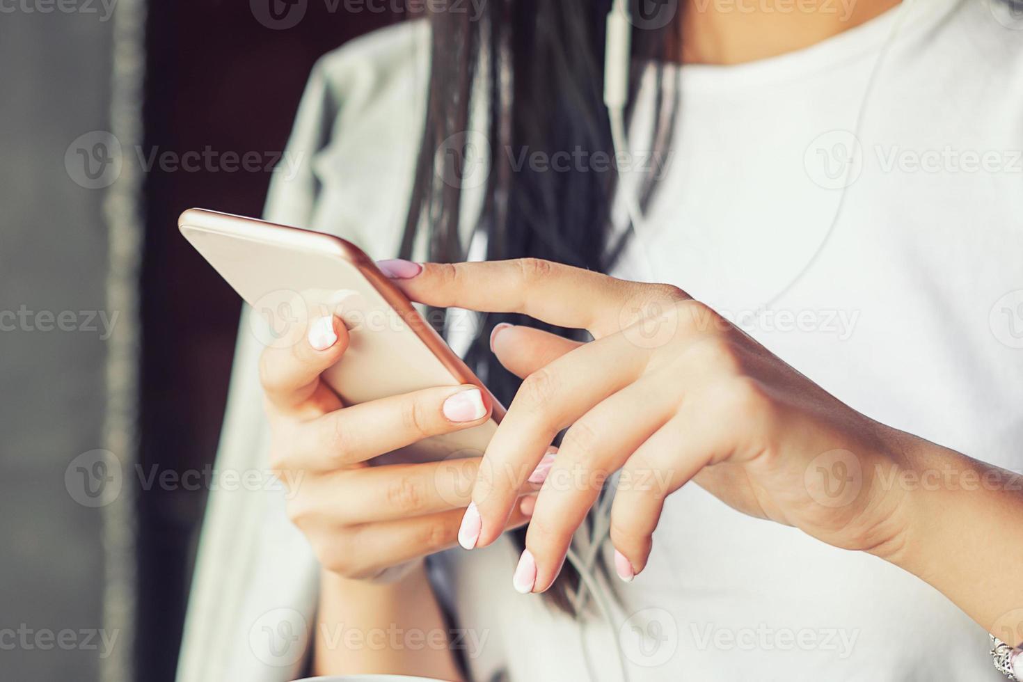 beautiful woman in glasses is listening music by her smartphone at cafe photo