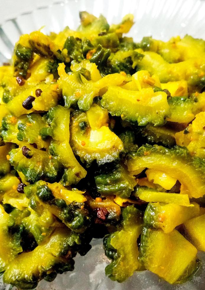 Cooked bitter Melon gourd or Karela Sabzi served in a glass plate photo