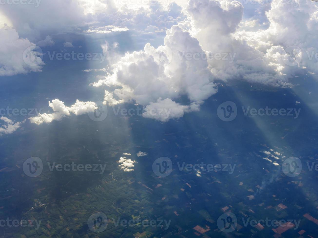 Aerial view flying above dramatic fluffy clouds and sun rays piercing shining through the clouds, sunny cloudscape, sunlight, Traveling by air photo