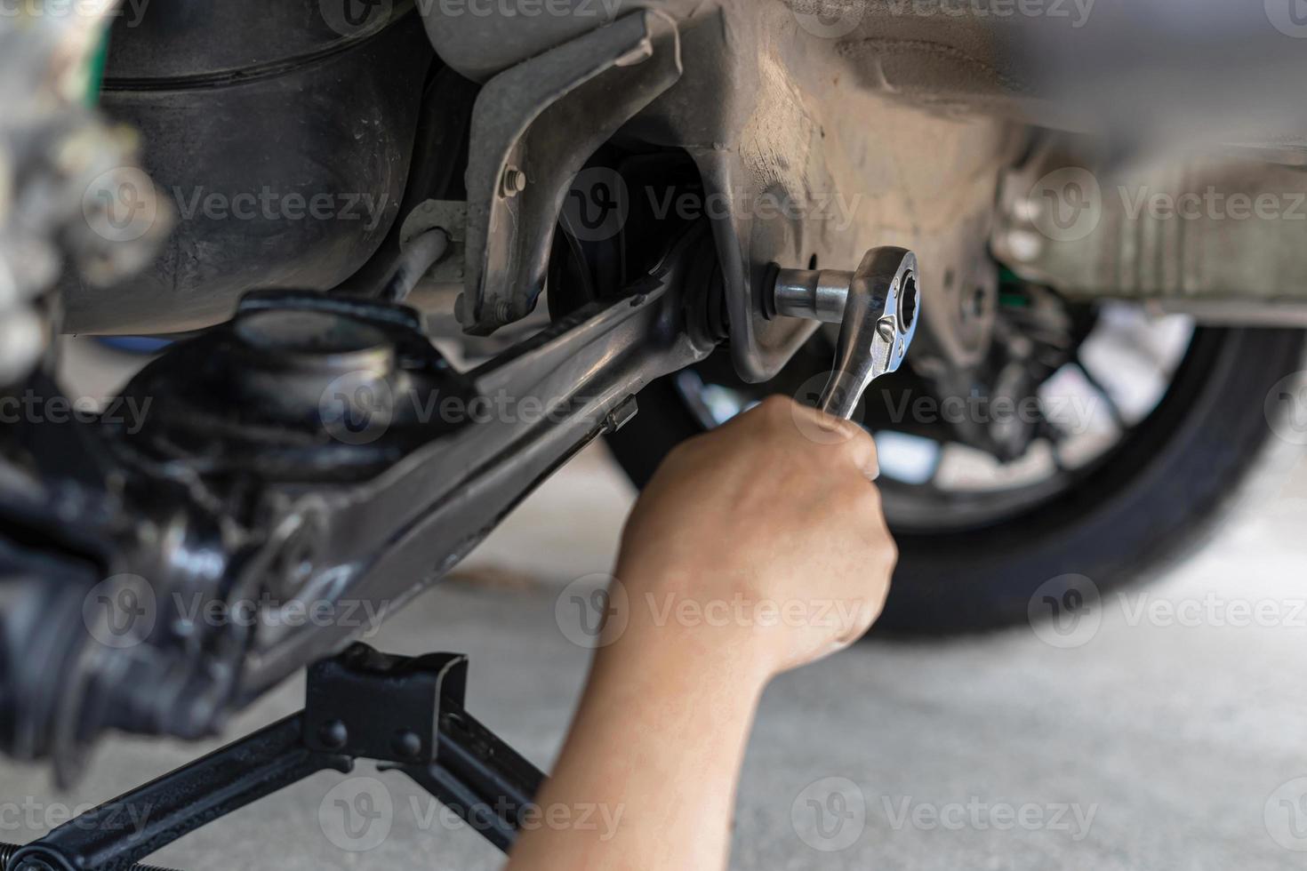 Close up wrench in hand a man adjust and lock bolt in car body in service concept of Suspension system photo