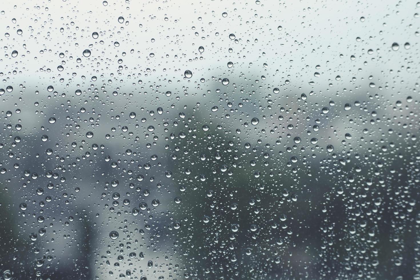 gotas de lluvia en la ventana con fondo borroso, día lluvioso, gota de agua en el vidrio, concepto de sensación de soledad. foto