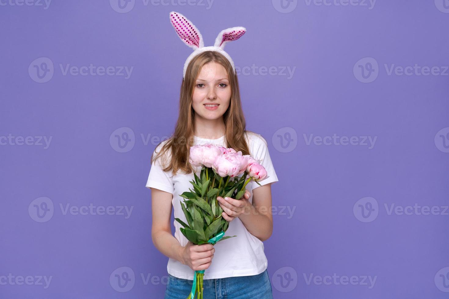 Smiling girl in rabbit ears on her head on purple studio background in white photo