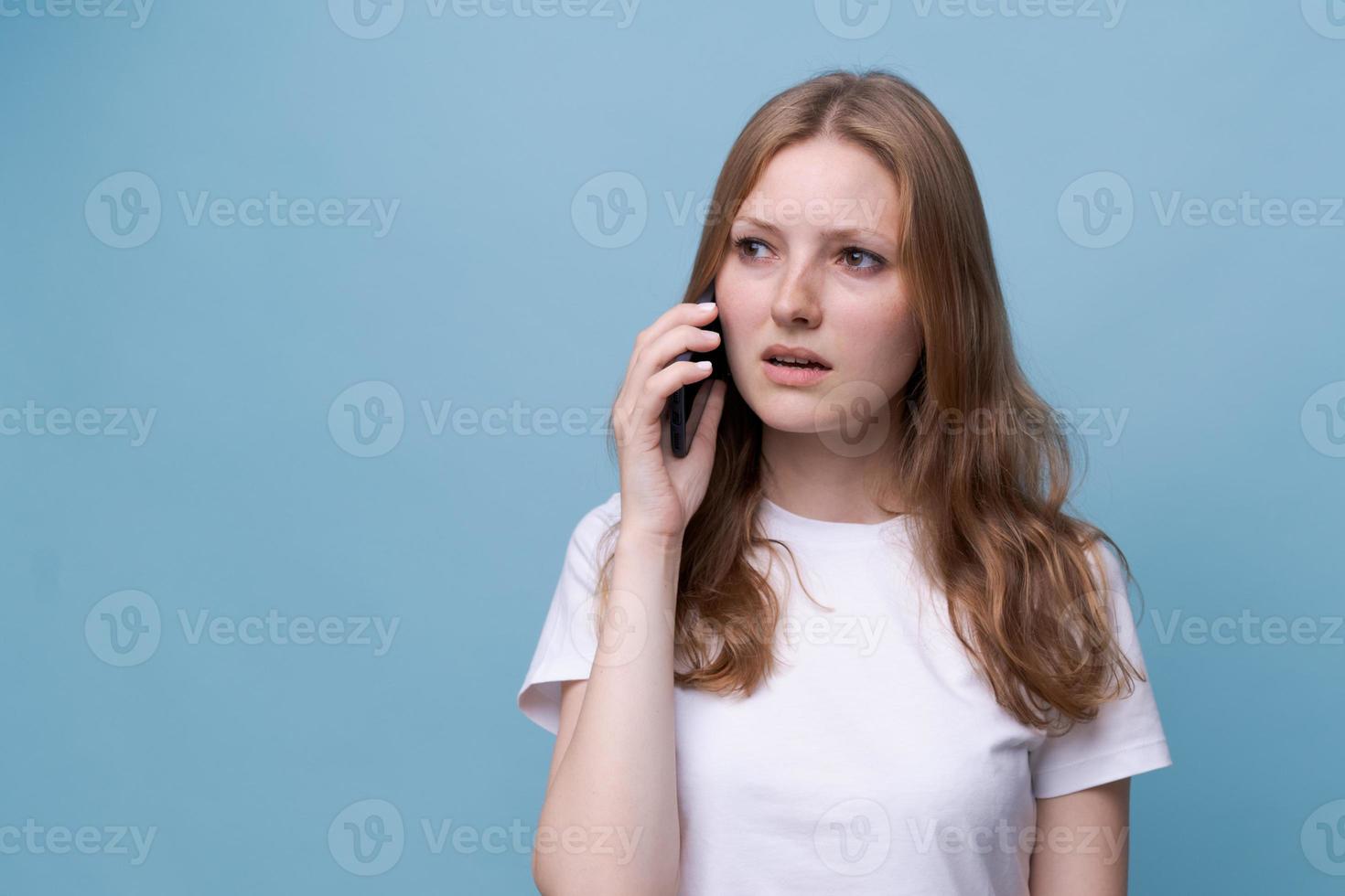 foto retrato sorprendido chica hablando por teléfono sobre fondo azul en blanco