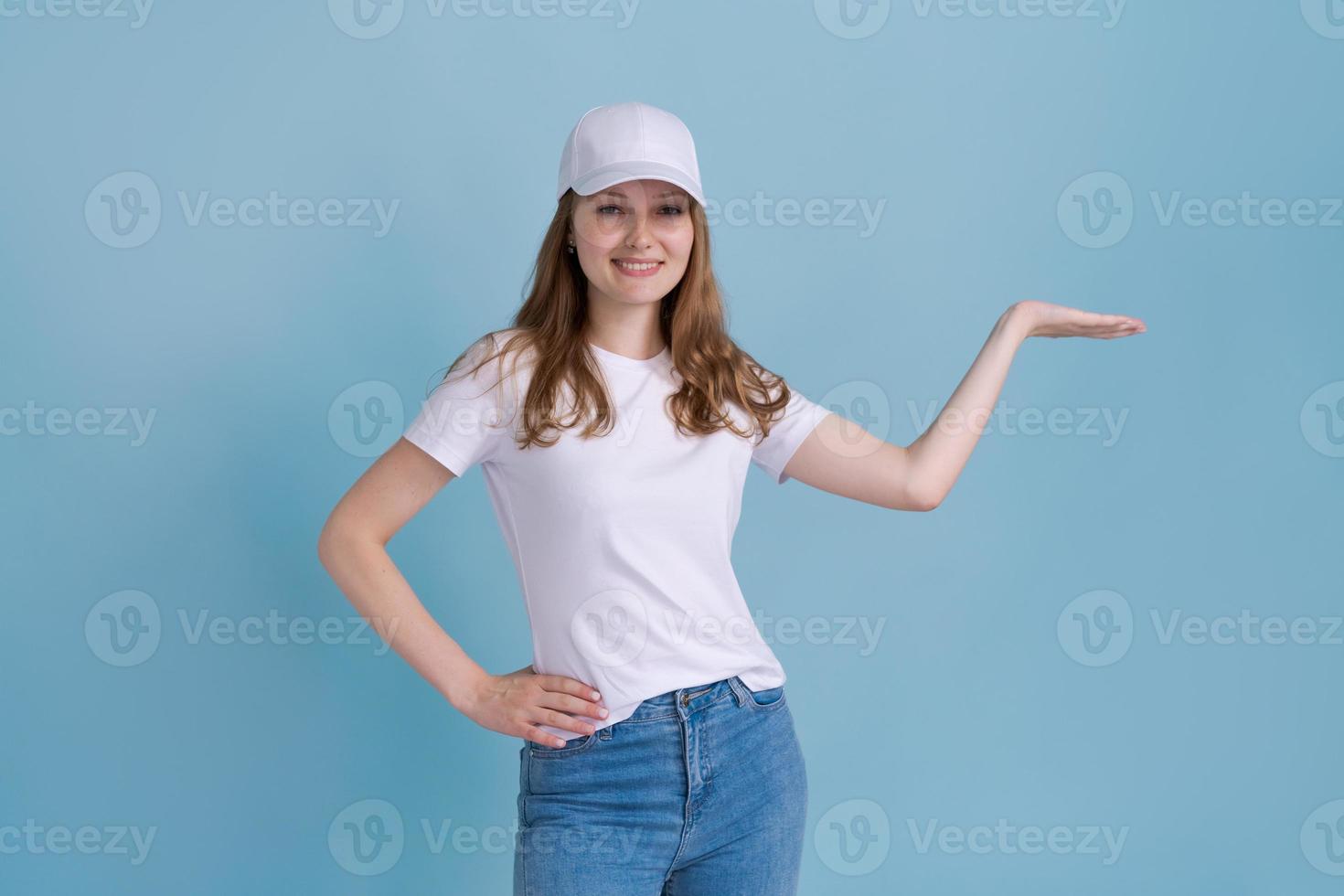 Cheerful young caucasian lady pointing at free space isolated on blue studio photo