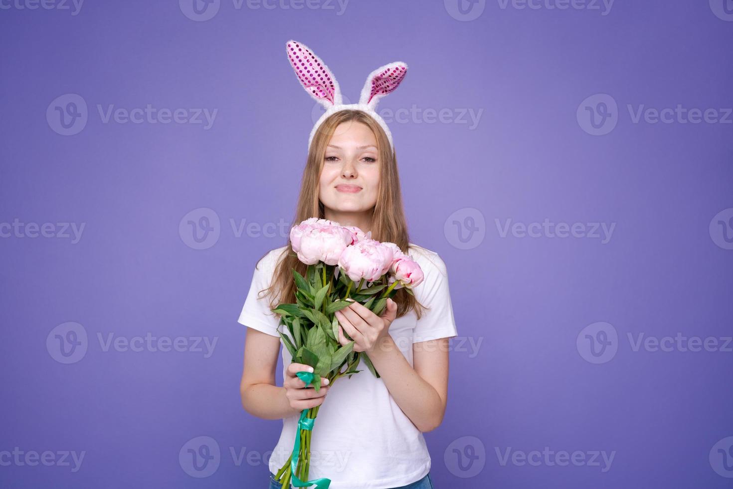 encantadora linda chica feliz con orejas de conejo rosa de pascua y ramo de primavera foto