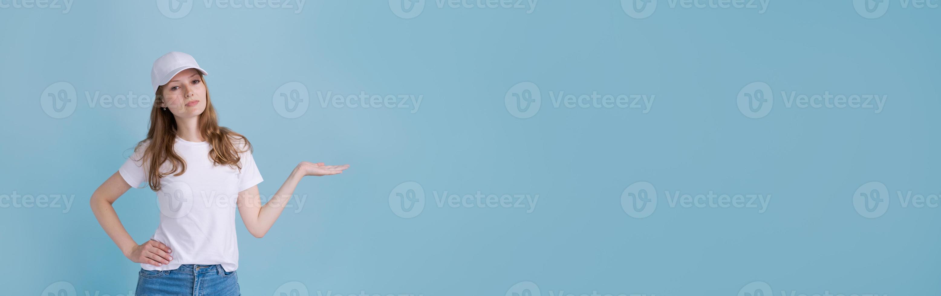 Cheerful young caucasian lady pointing at free space isolated on blue studio photo