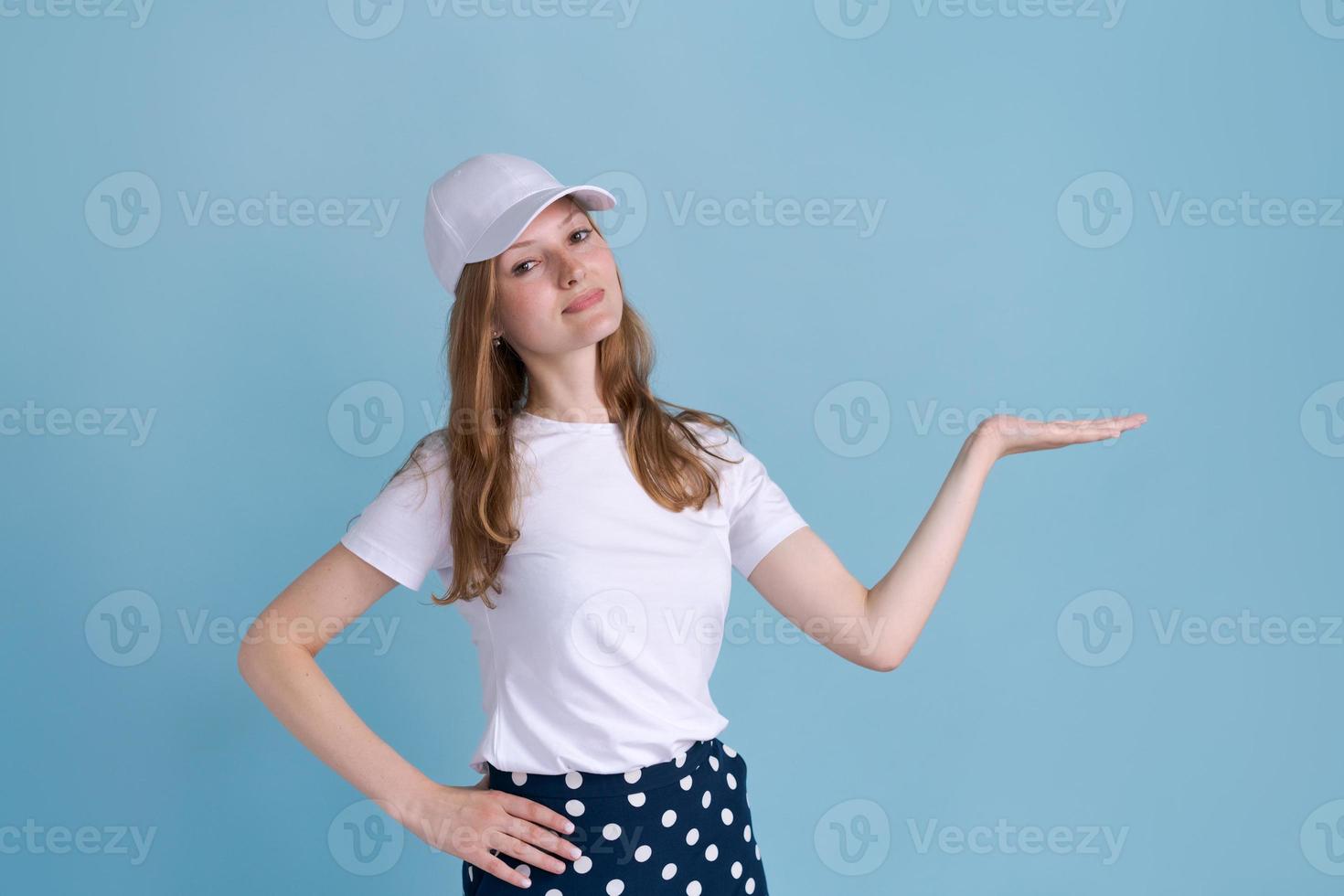 Cheerful young caucasian lady pointing at free space isolated on blue studio photo