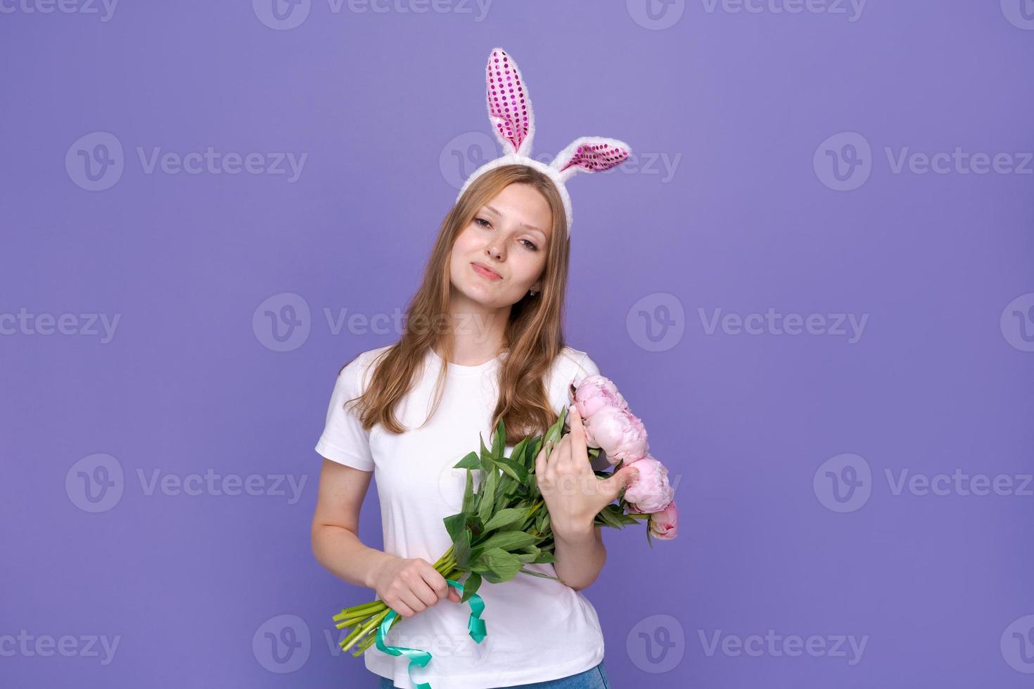 Smiling girl in rabbit ears on her head on purple studio background in white photo