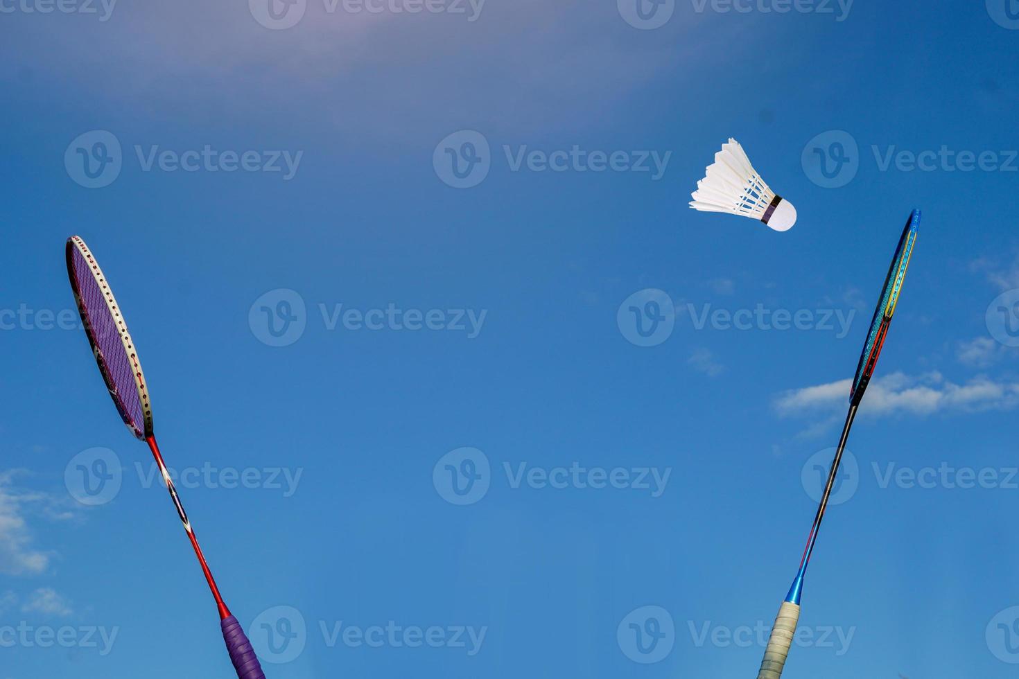 Badminton racket and white shuttlecock on cloudy sky background. Concept playing badminton outdoors. photo