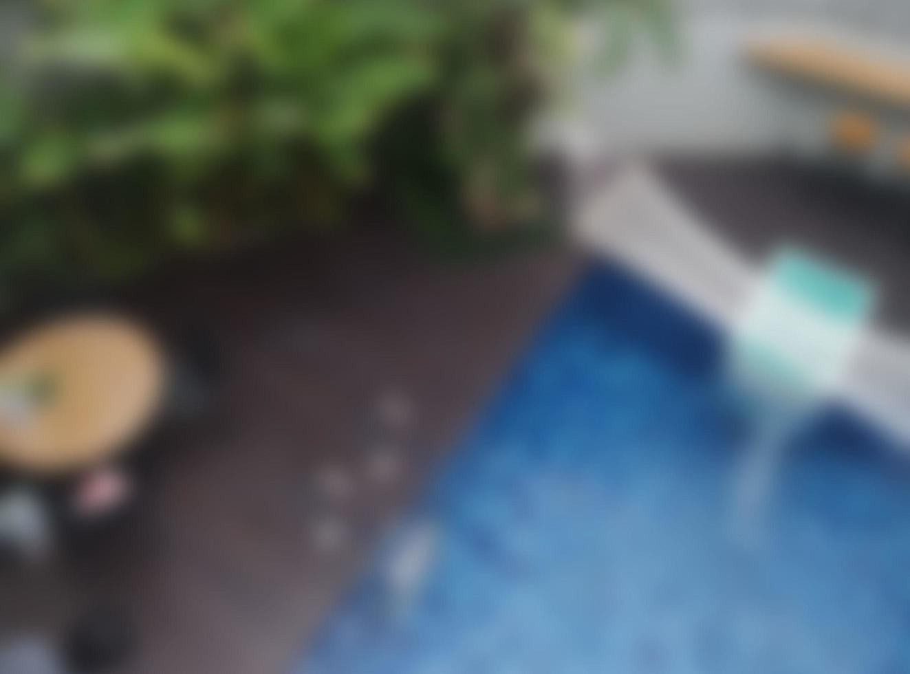 Defocused abstarct background of  The swimming pool is blue with some banana plants on the left and some chairs on the right photo