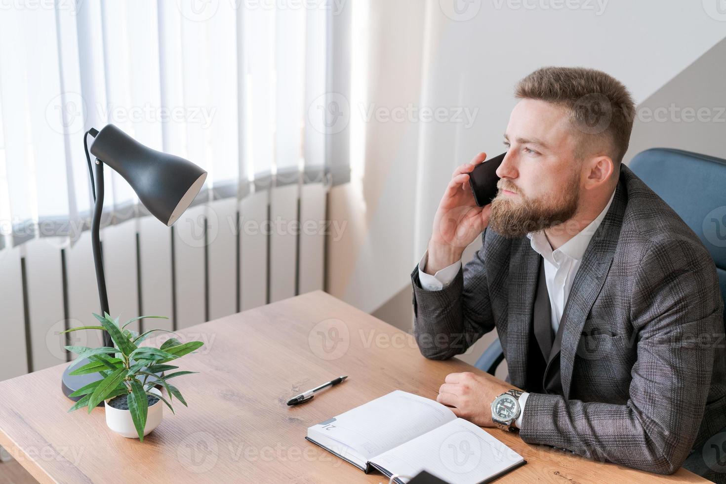 hombre barbudo de negocios está hablando por teléfono y planea reunirse a diario y escribir foto